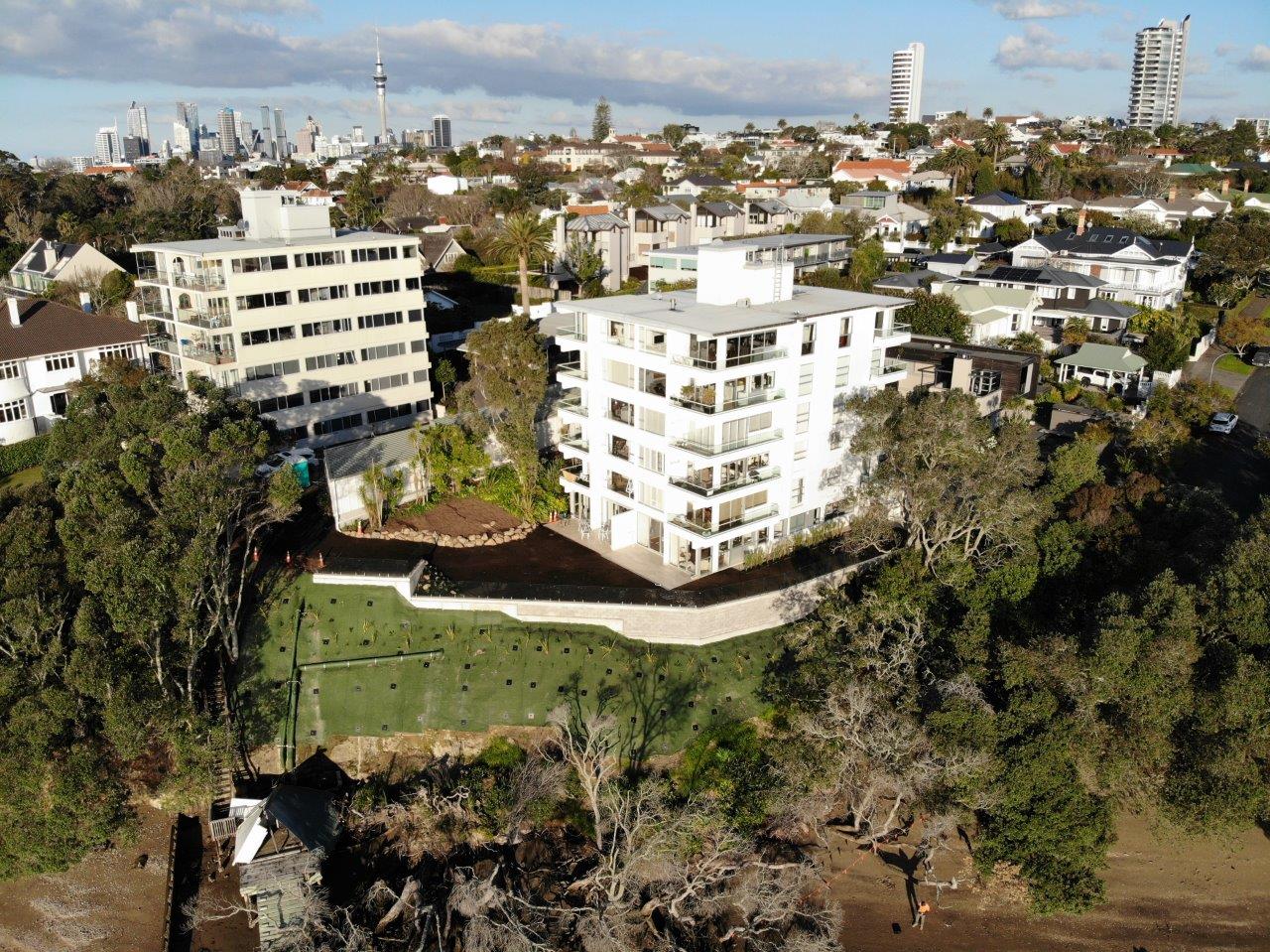 Aerial view of an anchored and meshed slope below clifftop apartments