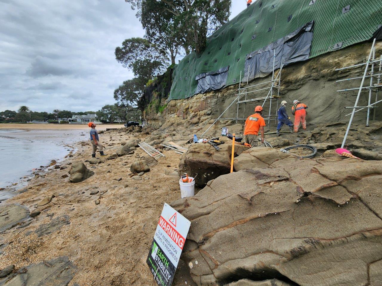 Crew applying sprayed concrete to a coastal rock face