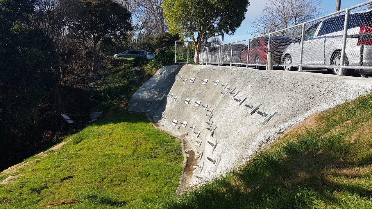 Completed anchored shotcrete retaining wall alongside a roadway