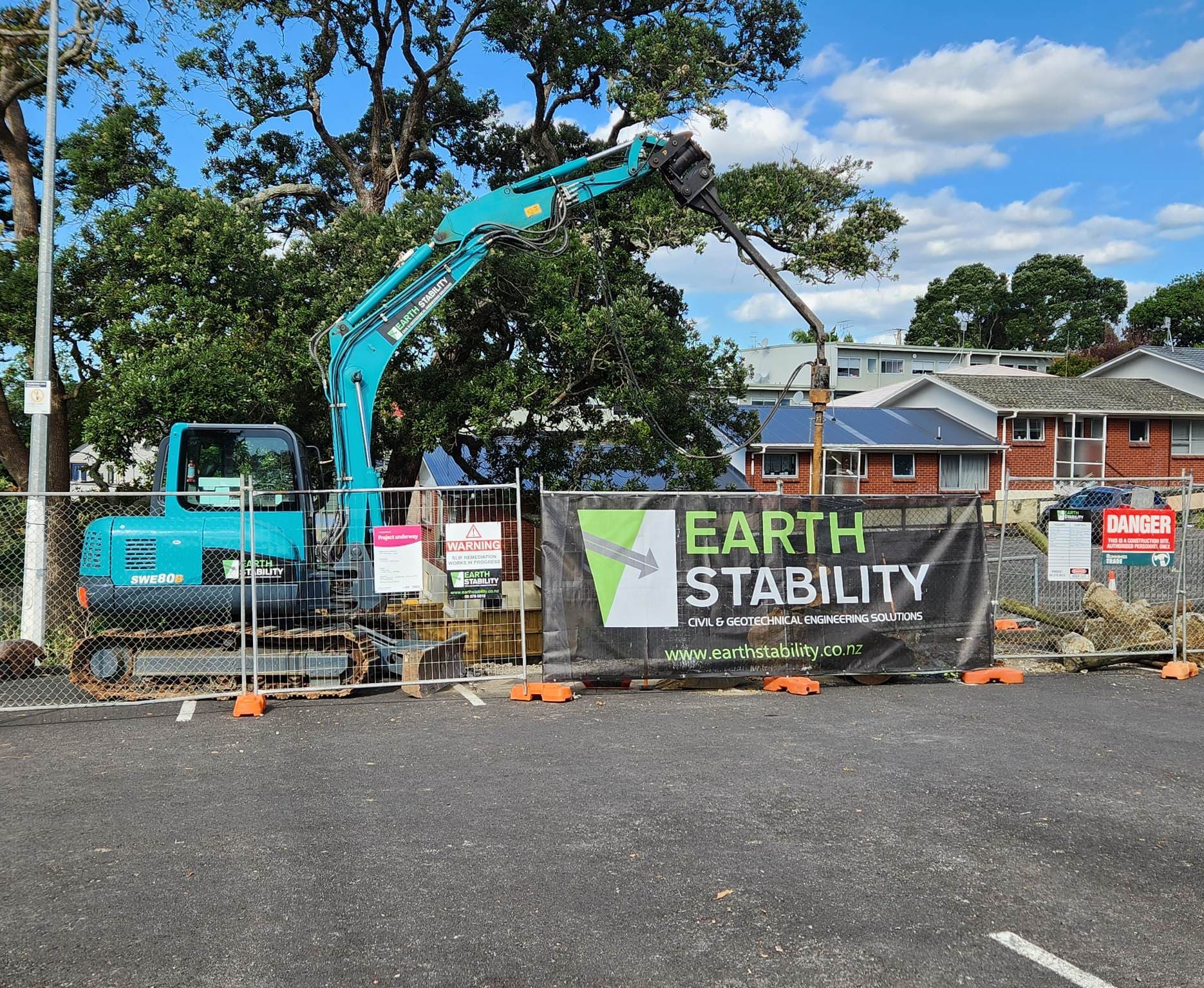 Branded excavator and Earth Stability signage on a secured residential site