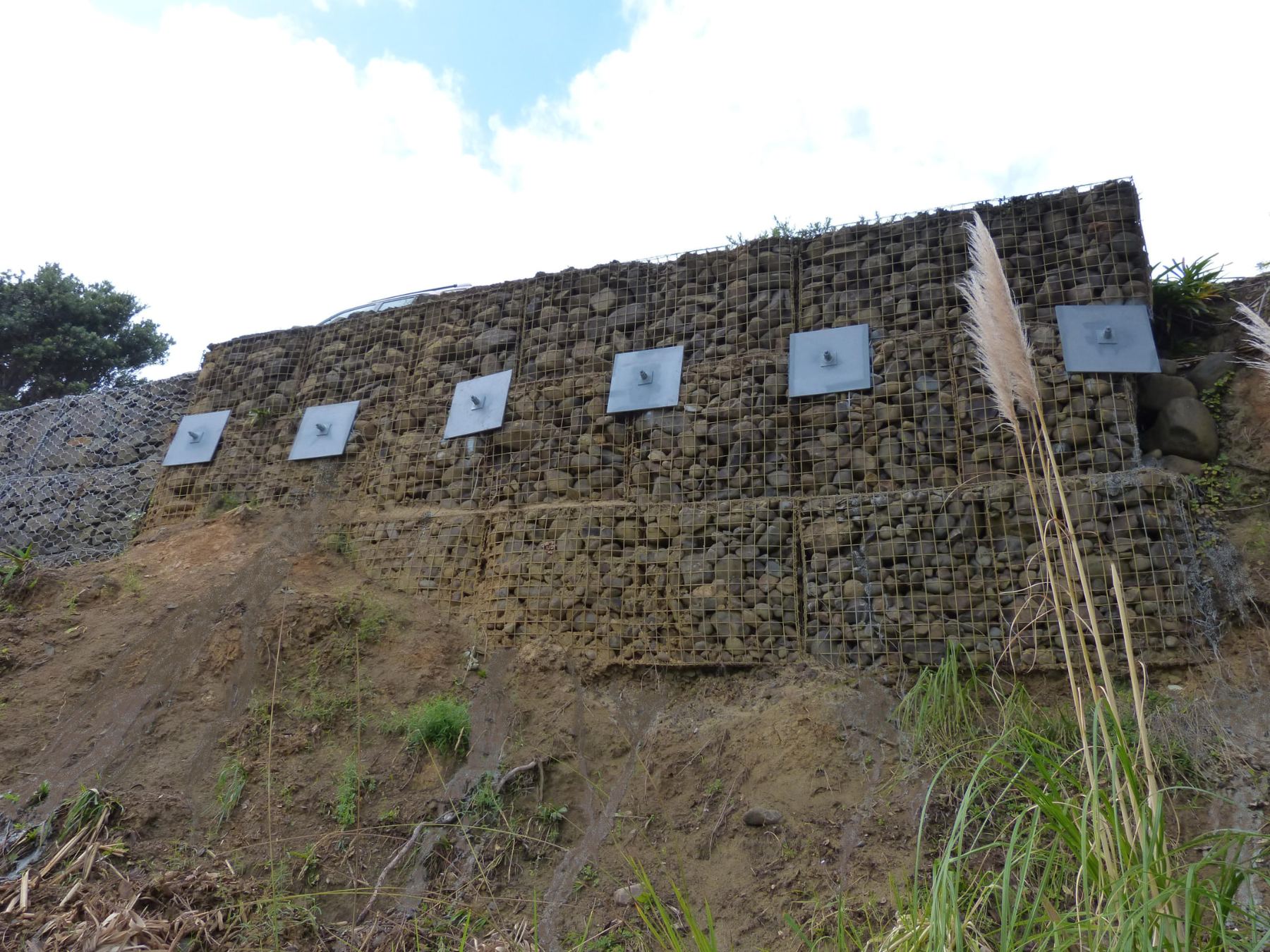 Failed gabion retaining wall being repaired with drilled ground anchors