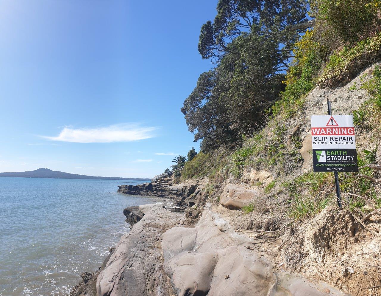 Slip repair warning signage on a coastal walkway above the water