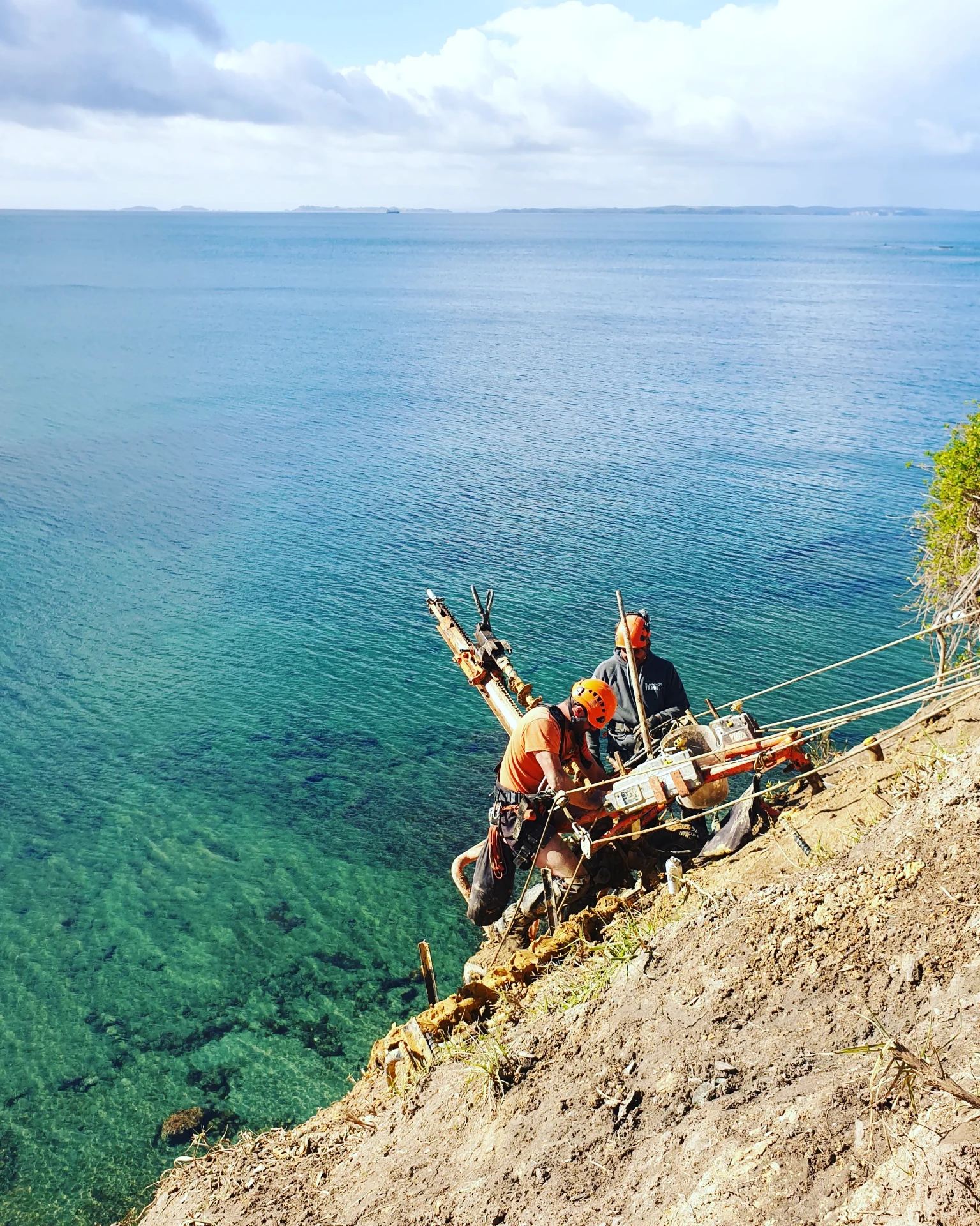 Geotechnical drill rig anchored to a coastal cliff face above the ocean