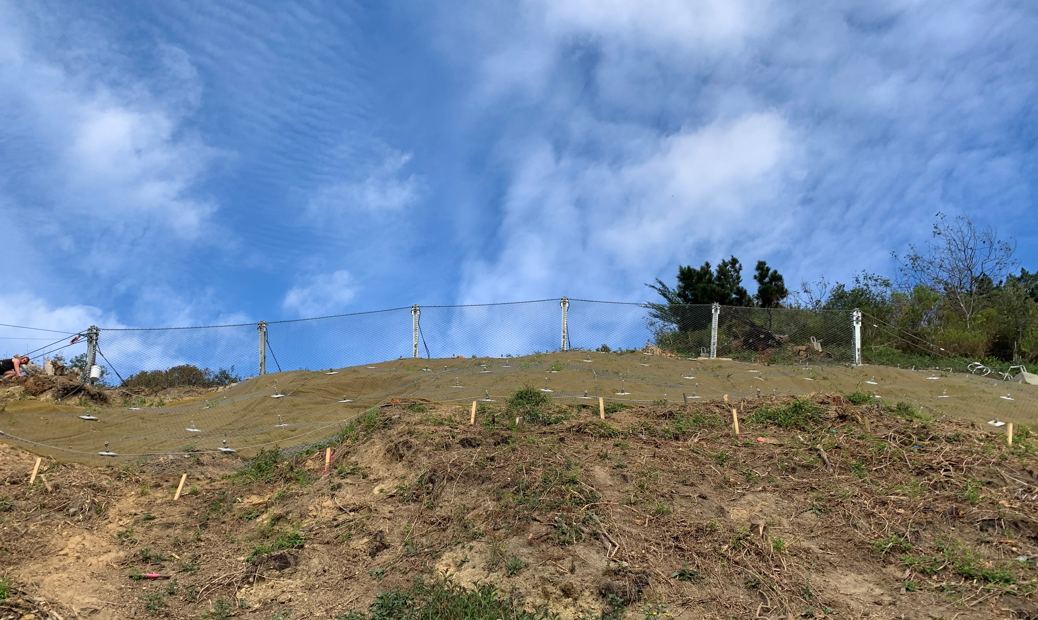 Slope during works, with erosion matting and catch fence posts installed
